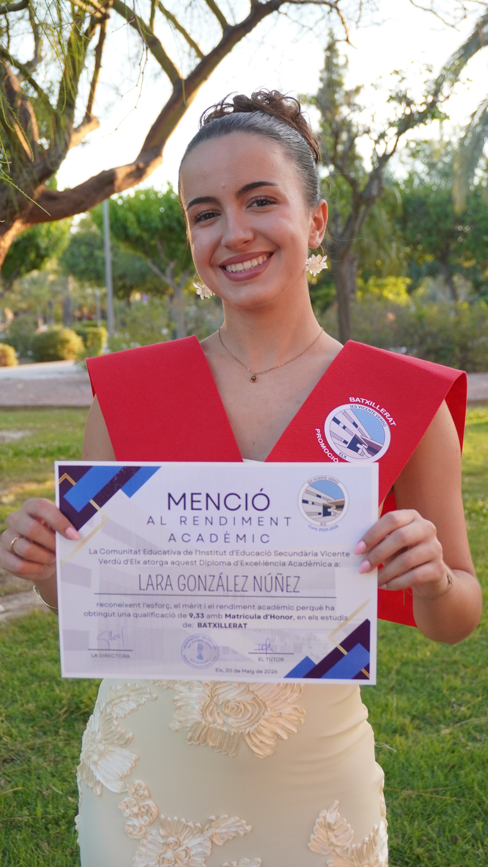 Lara con la beca roja de Bachillerato sostiene su diploma de Mención al Rendimiento Académico del IES Vicente Verdú de Elche: 9,33 con Matrícula de Honor en Bachillerato, 20 de mayo de 2026